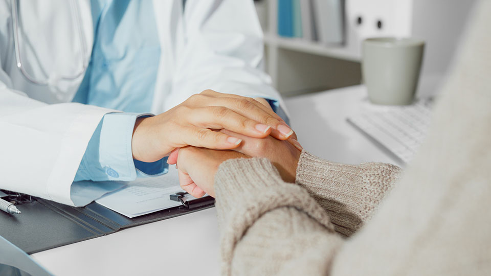 Oncologist hold hands of breast cancer patient
