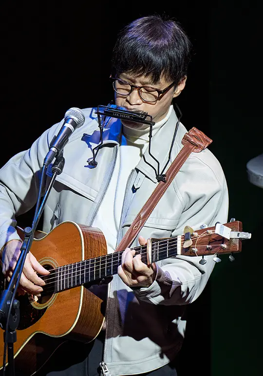 Haki Park in concert, playing the guitar and harmonica